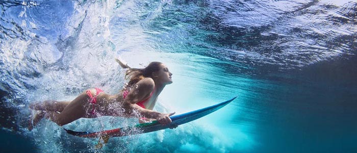 Young girl in bikini - surfer with surf board dive underwater wi